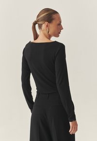 Must must sleeves, lai kaelus, pehmest kangast. Seljal on sujuv disain ja sobib hästi mustade kohandatud pükstega.