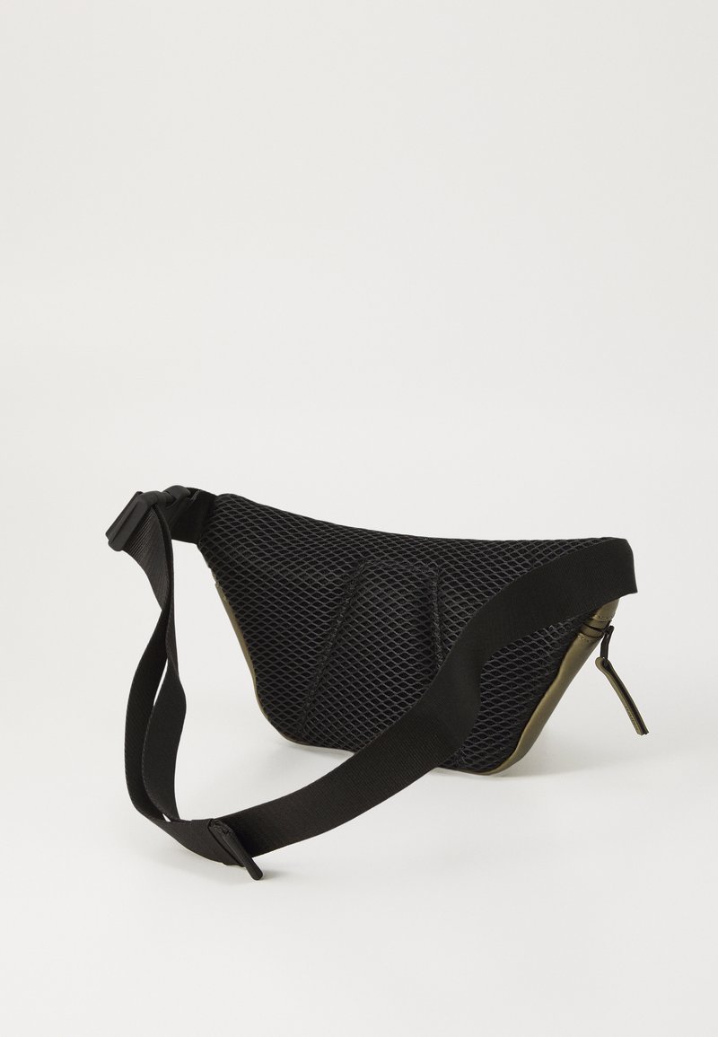 Borsa a rete nera con forma curva, fondo verde oliva liscio, tracolla regolabile e chiusura con zip. Dettagli di superficie texturizzata visibili.