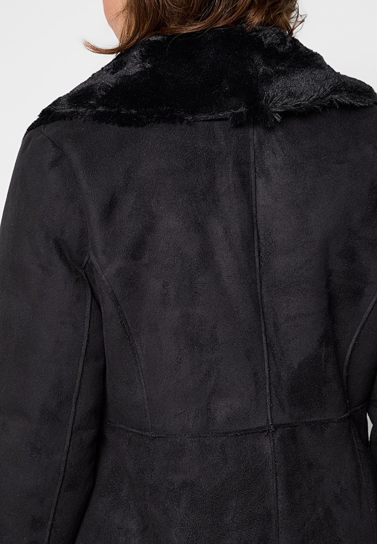 Giacca in faux suede nera con colletto in pelliccia nera morbida. Presenta cuciture senza soluzione di continuità e un design aderente che mette in risalto la silhouette della schiena.
