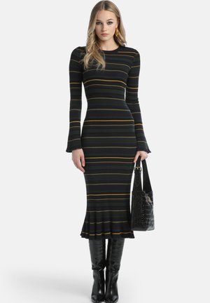 Sort og gulstribet ribstrikket kjole med klokkeærmer og en udsprunget kant, parret med knæhøje sorte patentstøvler og en taske med krokodillestruktur.