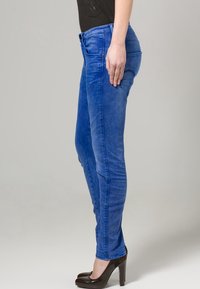 Tight jeans i livfull blå denim med medelhög midja, bälten, och klassisk fem-fickors design, ihop med högklackade skor.