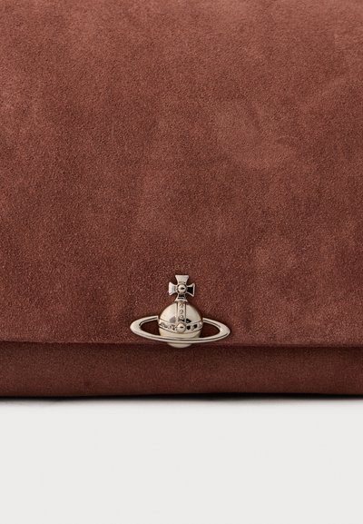 Smeđi nubuk clutch s srebrnim okruglim znakom i prstenom koji prikazuje križ i male ugravirane detalje centrirane bliže donjoj ivici.