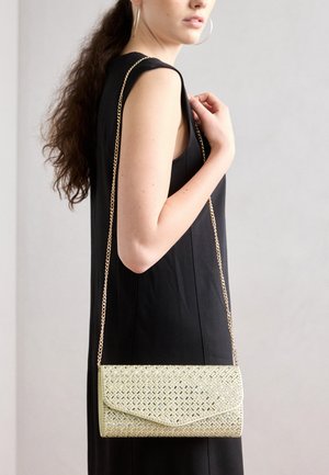 Kreemivärvi käekott, millel on kootud geomeetriline muster, koos volditava klapiga ja pika kuldse kettstrapiga.