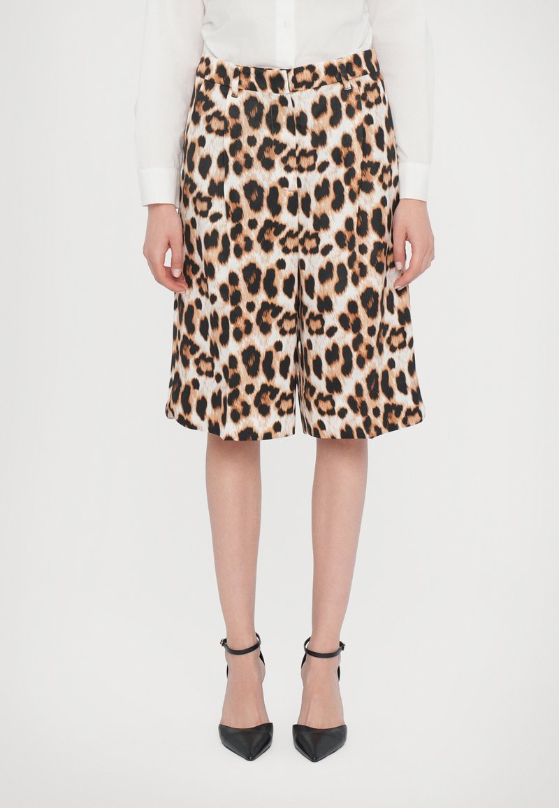 Leopard print shorts made of fabric, featuring an elastic waistband, loose fit, and a knee-length cut. Paired with black heeled shoes.