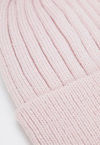 Bonnet en tricot rose présentant des côtes verticales et un détail subtil pailleté. Texture douce avec un revers plié pour plus de chaleur.