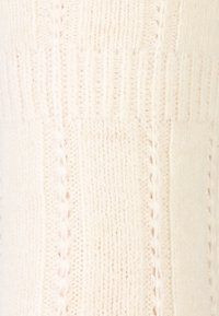 Tecido branco tricotado com um design texturizado em canelado. Apresenta riscas verticais e uma aparência suave e aconchegante. Sem padrões ou detalhes visíveis.