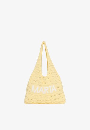 Gul hæklet indkøbstaske med et tekstureret bølgemønster og navnet "MARTA" strikket i hvid foran.
