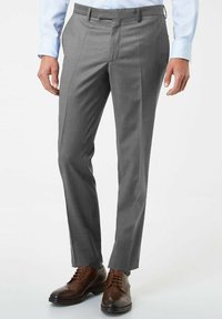 Pantalons de costume gris avec une coupe ajustée, présentant des plis à l'avant et une texture lisse. Associés à des chaussures en cuir marron à lacets.