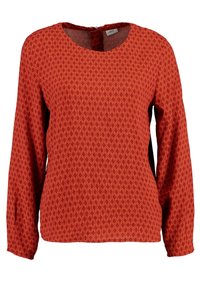 Blouse rouge à manches longues avec un motif géométrique de losanges sur l'ensemble et un col rond avec une petite fermeture éclair au dos.