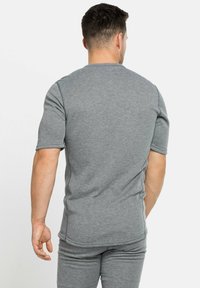 Chemise grise à manches courtes en tissu doux, dotée d'un col arrondi et d'une coupe décontractée, vue de dos avec une texture lisse.