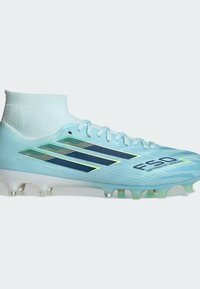 Chaussure de football bleu clair avec chaussette montante, rayures bleu foncé, lacets et crampons moulés sur fond blanc.