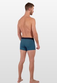 Boxers pour hommes en tissu bleu avec un motif géométrique. Comprend une taille marine, une coupe ajustée et une texture lisse.