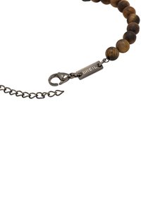 Braccialetto di perline con perline di legno marroni e nere, catena in argento e chiusura a molla con un'etichetta in argento incisa con la scritta "BREIL."