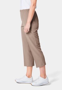 Beige, taillierte Hosen aus glattem Stoff, mit schmaler Passform, seitlichen Taschen und einem Bund, kombiniert mit weißen SportSneakern.