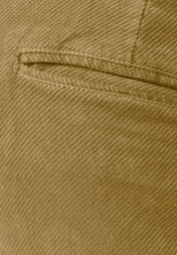 Braunes Cordstoffgewebe mit feiner gerippter Textur, ausgestattet mit einer Taschendetail und gesteppten Akzenten. Die Farbe ist einheitlich und ohne Muster.