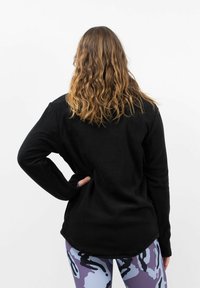Zwart fleece longsleeve top met een relaxte pasvorm, afgeronde zoom, geribbelde manchetten en een gladde textuur, gedragen met een gepatroonde legging.