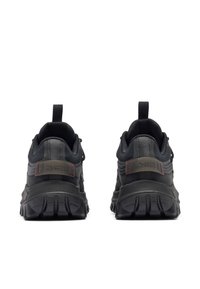 Musta urheilujalkine, jossa on teksturoitu päällinen, vahvistettu kanta ja kumipohja. Varustettu vetotapeilla ja punaisilla yksityiskohdilla sivuilla.