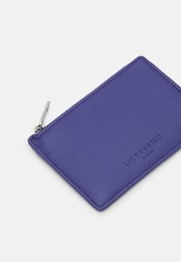 Fioletowy skórzany portfel o teksturowanej powierzchni, z zamknięciem na zamek błyskawiczny i wytłoczonym logo. Kwadratowy kształt z zaokrąglonymi krawędziami.