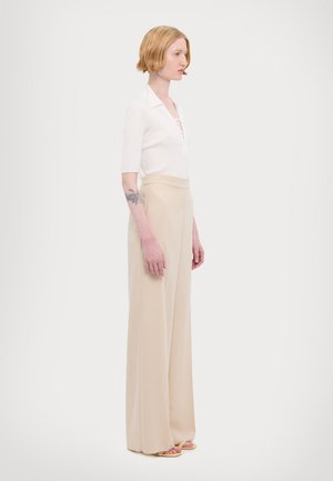 White ribbed short-sleeve top with lace-up detail paired with beige wide-leg trousers, featuring a smooth texture and high waist design.