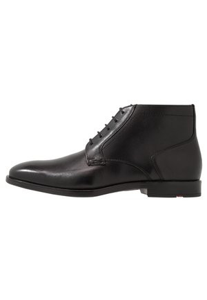Bottes courtes en cuir noir avec un bout arrondi, une texture lisse, des lacets à six œillets et une semelle en caoutchouc profilée basse. Accents de design minimalistes.