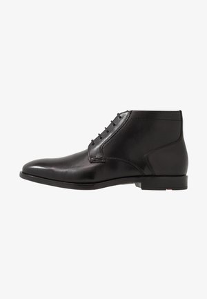 Bottes courtes en cuir noir avec un bout arrondi, une texture lisse, des lacets à six œillets et une semelle en caoutchouc profilée basse. Accents de design minimalistes.