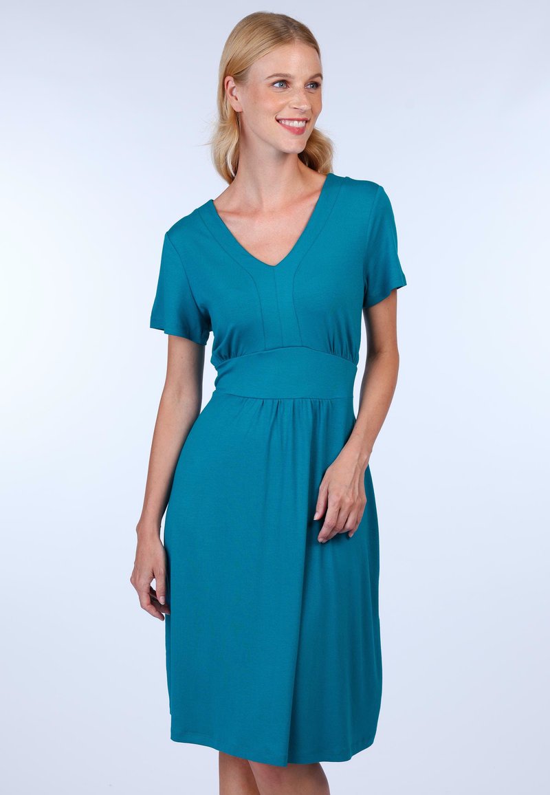 Teal Kleid aus weichem Stoff, mit V-Ausschnitt, kurzen Ärmeln, tailliertem Oberteil und fließendem Rock. Einfaches Design ohne sichtbare Muster.