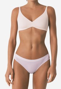 Lichtroze bralette met een V-hals en dunne bandjes; gecombineerd met witte low-rise slips met een subtiele logo op de tailleband. Glad textuur.