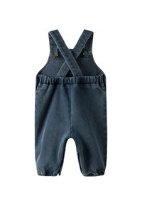 Imikute denimpüksid ristuvate selja rihmade ja elastse vöökohtadega, esitatud valge taustaga.