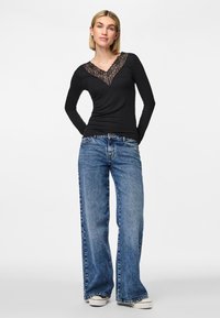 Must have musta sleeves with lace V-kaelus, koos heledate siniste laiade pükstega ja valgete tossudega, neutraalse taustaga.