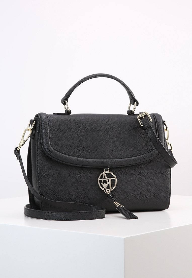 Svart syntetiskt läderhandväska med en strukturerad design, överhandtag, avtagbar axelrem och detaljer i guldton. Har en logocharm och klaffstängning.