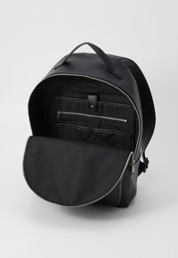Svart ryggsäck med en slät yta, dragkedjestängning och ett öppet huvudfack som avslöjar fickor för organisering. Hållbart material.