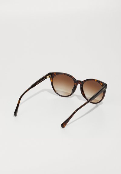 Schildpatt-Sonnenbrille mit einem Verlauf von braunen Gläsern, runden Rahmen und eleganten dunklen Bügeln. Auffälliger goldener Akzent an der Innenseite des Rahmens.