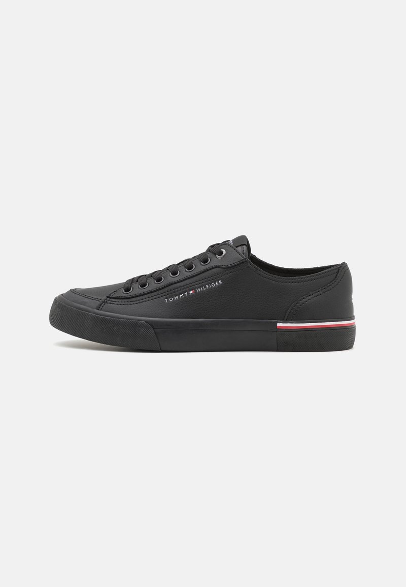 Basket basse noire avec lacets noirs, semelle en caoutchouc, détail à rayures rouges et blanches, et logo Tommy Hilfiger sur le côté.