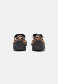 Et par leopardmønstrede slip-on sko med sorte såler, vist fra bagsiden på en ensfarvet hvid baggrund.
