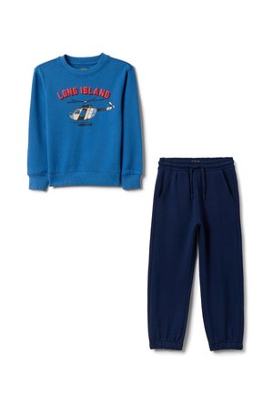 Sudadera azul con el texto "LONG ISLAND" y gráfico de un helicóptero, combinada con pantalones jogger azul marino con cintura ajustable y puños elásticos.