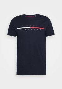 Camiseta de algodón azul marino con mangas cortas. Presenta un diseño de logo horizontal en blanco, rojo y azul. Cuello redondo clásico.