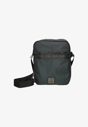 Black nylon crossbody bag with a zippered front pocket, adjustable strap, and logo patch. Compact square shape, sleek design.