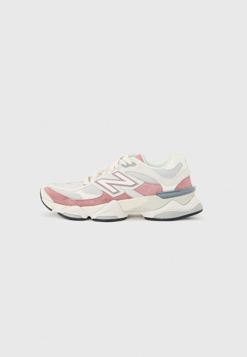Baskets New Balance blanches et roses avec panneaux en maille et en daim, semelle coussinée et design à lacets, présentées en profil sur fond gris.