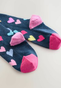 Chaussettes bleu marine avec des motifs en forme de cœur rose, bleu clair et jaune. Accents rose au niveau des orteils et du talon, fabriquées en tissu doux et texturé.