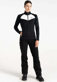 Schwarz-weiße Zip-Jacke mit hohem Kragen und langen Ärmeln, kombiniert mit schwarzen Hosen. Das Material scheint leicht und dehnbar zu sein.