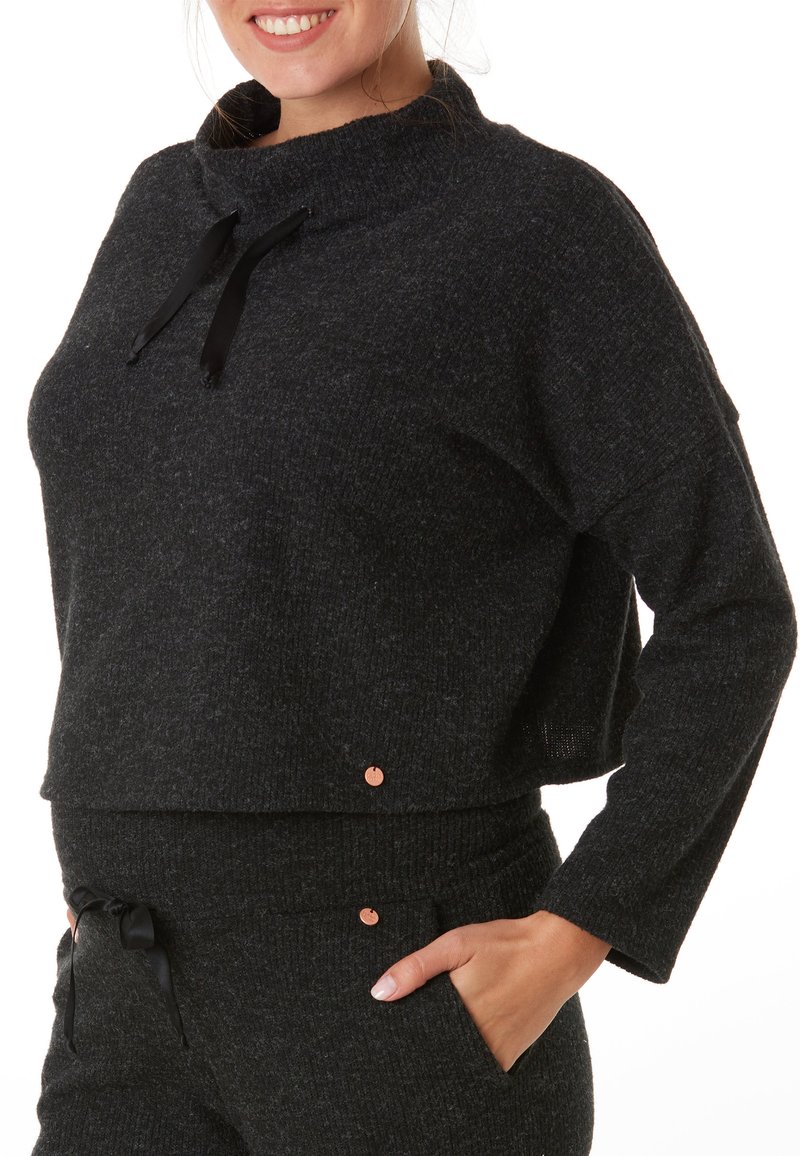 Pull en laine cropped gris foncé avec un col haut, des cordons de serrage noirs et une texture subtile ; présente un accent cuivré près de l'ourlet.