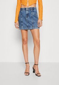 Denim mini hame, jossa on hieman kulunut pinta, elastinen vyötärö, etutaskut ja klassinen sininen väri.