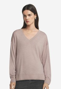 Ljusrosa, överstor V-ringad tröja med långa ärmar, ribbade manschetter och nederkant, gjord av ett mjukt stickat tyg.