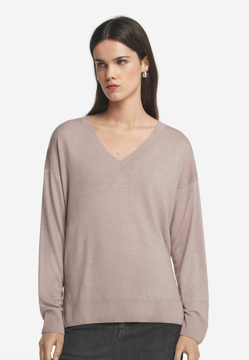 Ljusrosa, överstor V-ringad tröja med långa ärmar, ribbade manschetter och nederkant, gjord av ett mjukt stickat tyg.