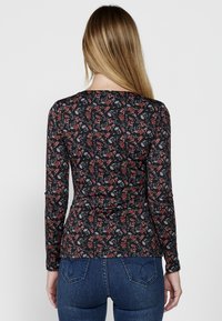 Langärmliges, eng anliegendes Oberteil in Schwarz mit floralem Muster, das rote und weiße Blumen zeigt. Hergestellt aus weichem Stoff mit glatter Textur.