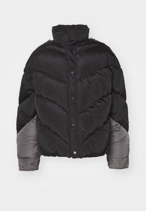 Zwarte pufferjack met hoge kraag, drukknoopsluiting, chevron-quiltpatroon en grijze accenten op de mouwen. Zacht, geïsoleerd materiaal.