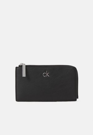 Billetera de cuero negra con cierre de cremallera, que presenta un logo plateado y una textura suave, forma rectangular y diseño minimalista.