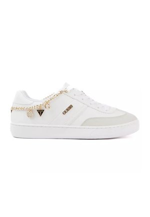 Sneaker bianca con catena dorata e ciondoli laterali, con il logo "GUESS", presentata su sfondo bianco semplice.