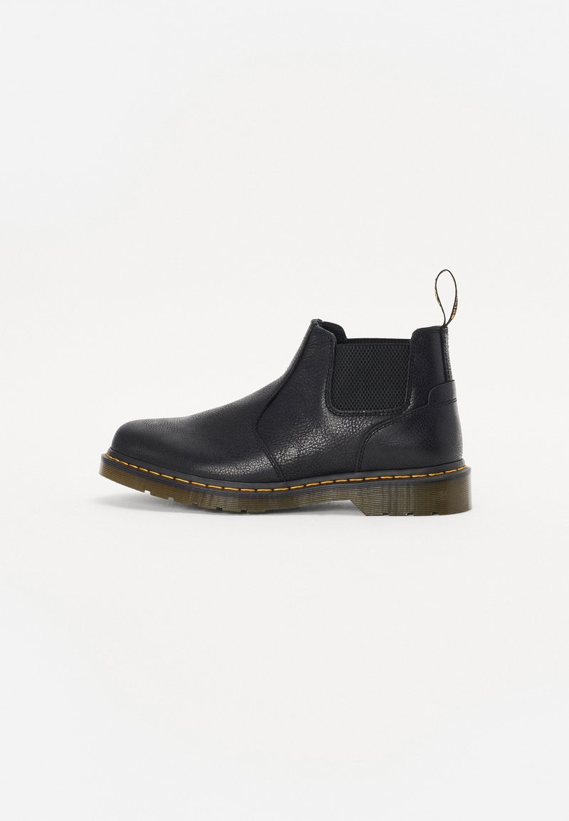 Bottine Chelsea en cuir noir avec panneaux latéraux élastiques, semelle en caoutchouc marron avec couture jaune et languette à l'arrière.