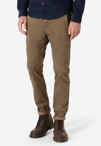 Brown corduroy trousers with a straight fit, featuring a subtle ribbed texture. Worn with dark lace-up leather boots.